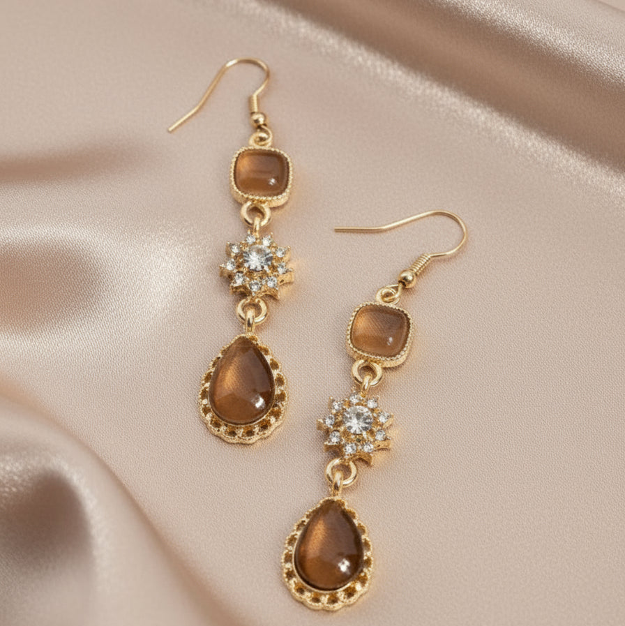Pair of gold and brown earrings on a white background
