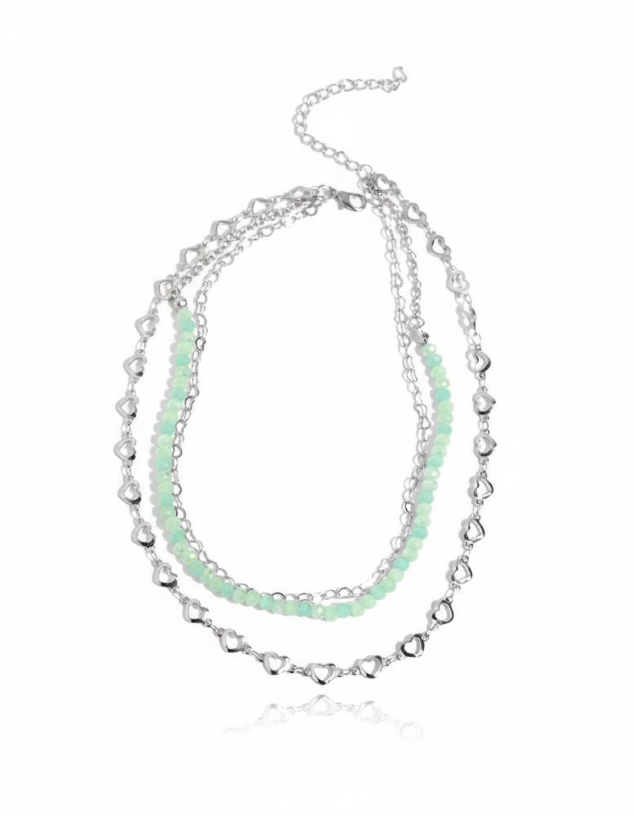 Stack of silver and light green beaded necklaces on a white background