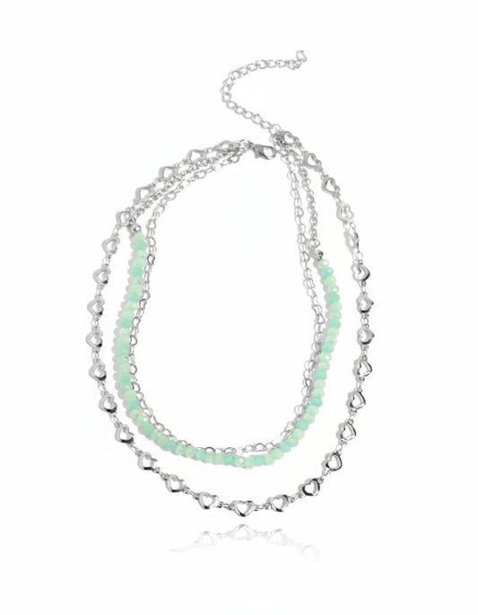 Stack of silver and light green beaded necklaces on a white background